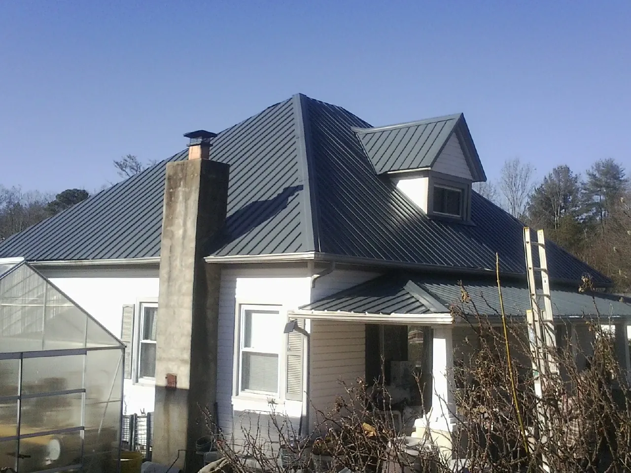 Dark blue standing seam metal roof on a white farmhouse with dormer — Slate & Tile Roof Repair by Roofing Brothers in Ivanhoe