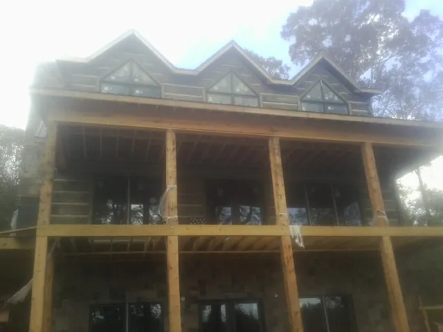 Dormers and porch framing on a large log home under construction — Roof Coating work by our crew in Ivanhoe