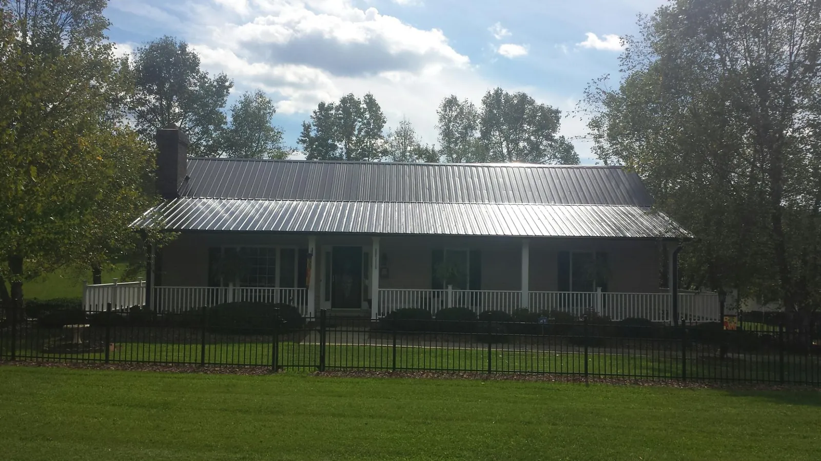 Gray metal roof on a brick ranch with a full width front porch — Gutter Guard Installation work by our crew in Ivanhoe